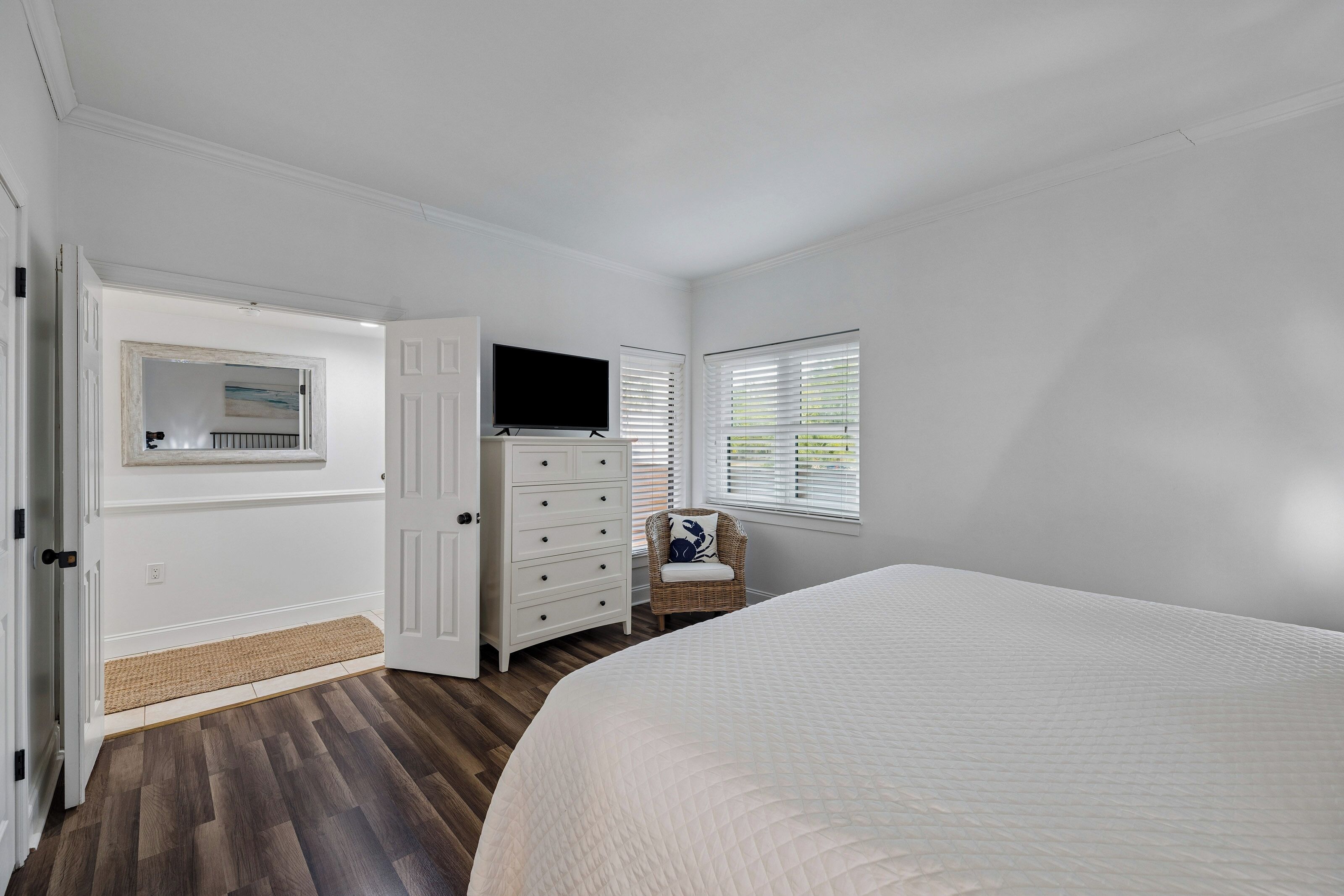 A bedroom with a bed, a dresser, a television, and a window with blinds.