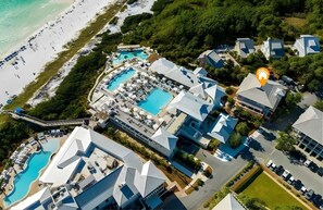 Vue aérienne d’un complexe hôtelier doté de plusieurs piscines, d’un accès à la plage et d’une architecture moderne.
