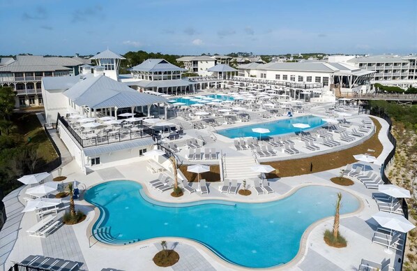 Un complexe hôtelier doté de plusieurs piscines, de chaises longues et d’un grand bâtiment surmonté d’une terrasse sur le toit.