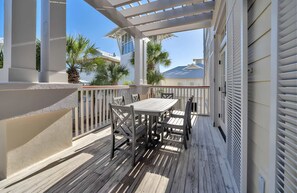 A covered outdoor patio with a table and chairs, white railings, and a view of a house with a sloped roof. - Closest Condo to Beach Club, Partial Gulf Views (Santa Rosa Beach)