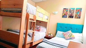 A room with bunk beds, a desk, and a wall with three paintings. - Cozy Apartment with View of Historic Cusco - Excellent Location-600Mbps (Cusco)