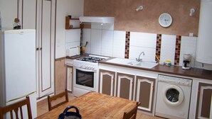 Pieni, käytännöllinen keittiö, jossa on kaasuliesi, uuni, pesuallas ja pyykinpesukone.