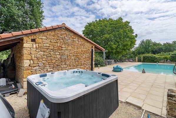 Ein Steinhaus mit Whirlpool, Schwimmbad und Außenbereich mit Sitzgelegenheiten.