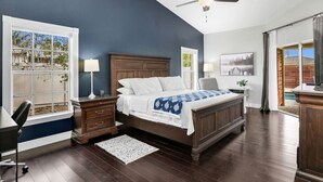 Une chambre avec un grand lit, un ventilateur de plafond, une fenêtre donnant sur l’extérieur et un bureau avec une chaise.