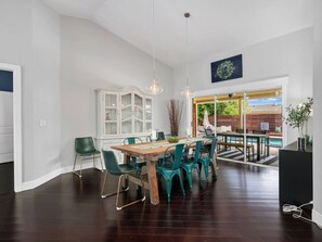 Ein großzügiger Essbereich mit Holztisch und blaugrünen Stühlen, einem weißen Schrank und Blick auf eine Außenpatio mit Pool.