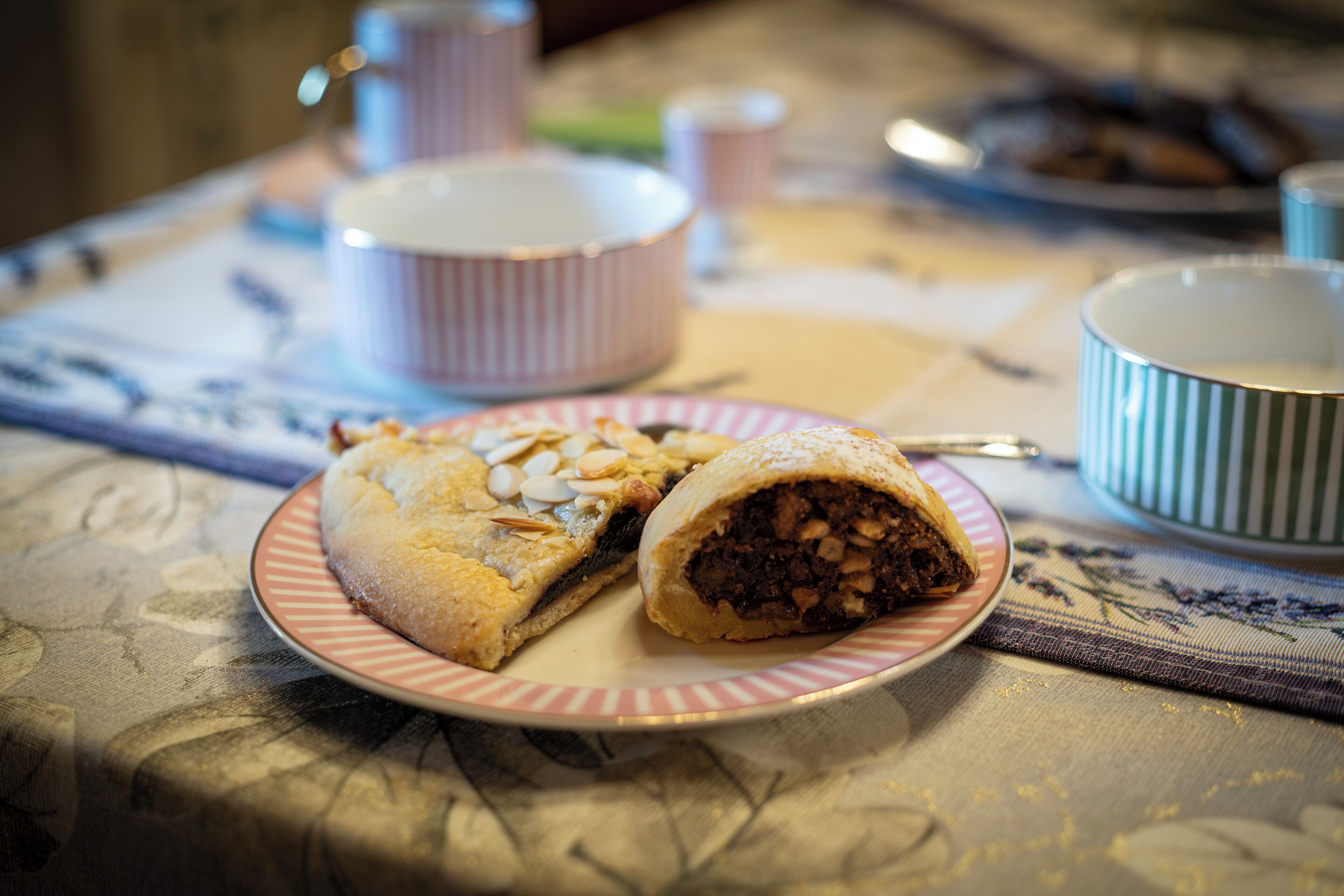 A plate with a pastry on a table with a patterned tablecloth.