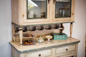 A vintage-style tea set with a green box labeled "TEA" on a wooden cabinet with glass doors. - Your ideal home surrounded by beauty and elegance, for moments of true relaxation (Spello)