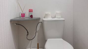A small, clean bathroom with a toilet, bidet, and a trash bin.