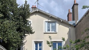 A two-story building with a flat roof, a small front yard with artificial grass, and a wooden bench. - Appartement 2 Chambres Business Famille (Orléans)