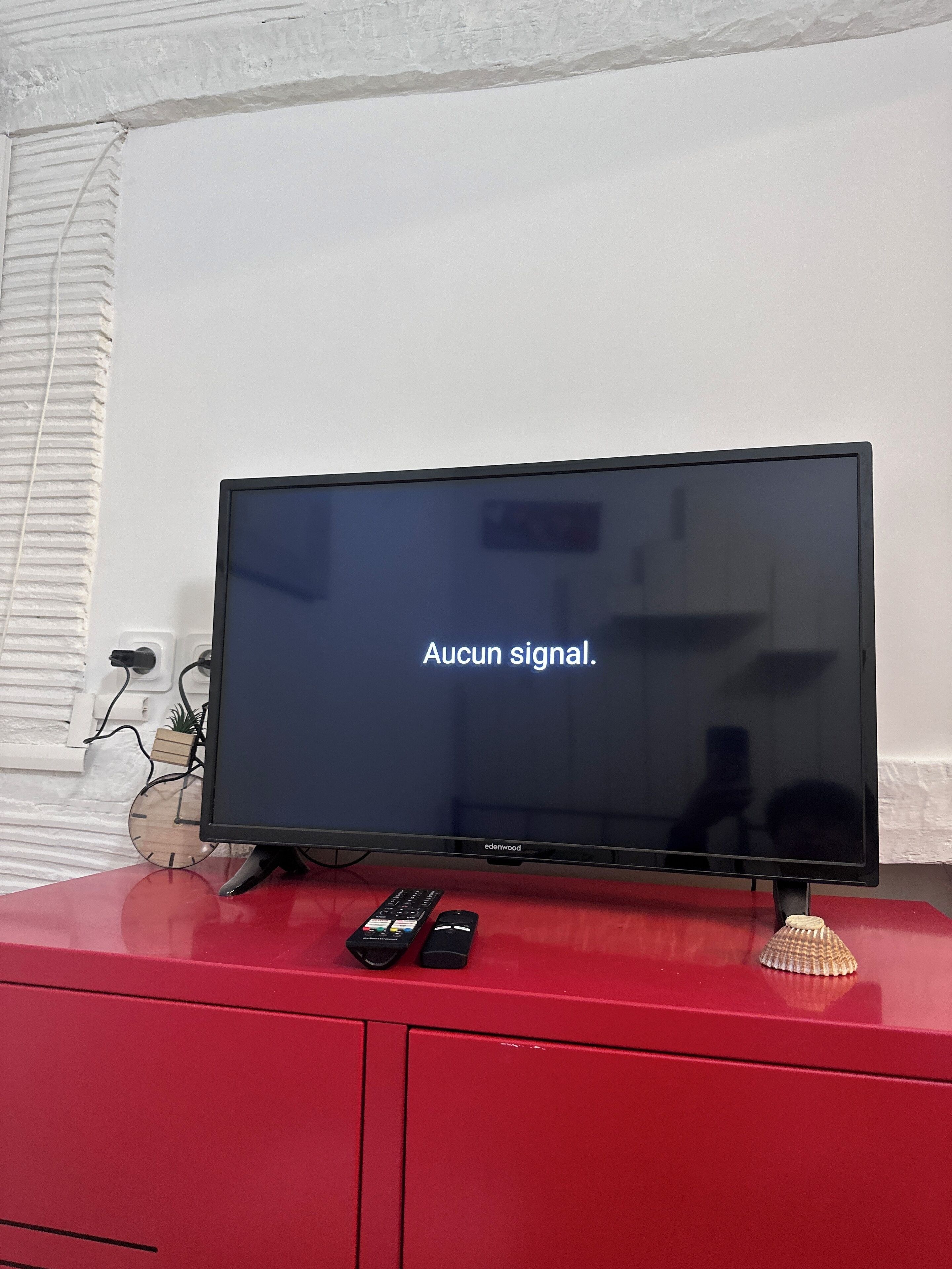 A television on a red cabinet displaying "Aucun signal."