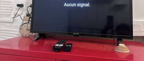 A television on a red cabinet displaying "Aucun signal."
