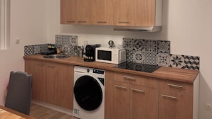 A modern kitchen with wooden cabinets, a microwave, a coffee maker, and a washing machine. - Appartement 2 Chambres Business Famille (Orléans)