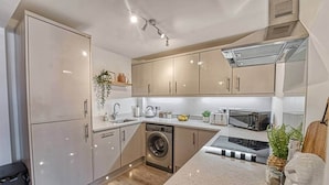 Una cocina moderna con electrodomésticos de acero inoxidable, lavadora integrada y encimera de granito.
