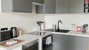 Una cucina moderna con mobili grigi, forno a incasso, lavello e macchina da caffè.
