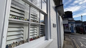 Een gebouw met een witte gevel en een etalage vol beeldjes.