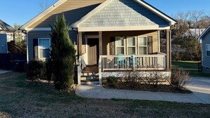A single-story house with a front porch, a small garden, and a clear blue sky.