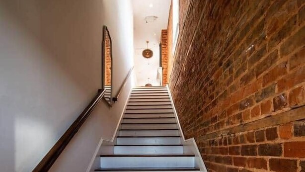 A staircase with wooden steps and a brick wall on one side. - The Nest Above - Finch Suite (Seneca)