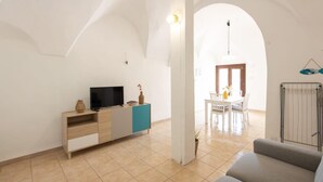 Ein Wohnzimmer mit Fernseher, ein Essbereich mit Tisch und Stühlen sowie eine Heizung.