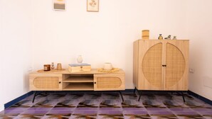 Ein Zimmer mit einem Holzkasten, einem kleinen Tisch mit Dekoration und einer großen gewebten Tür.