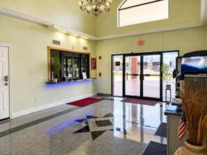 Vestíbulo de hotel con una mesa de recepción, una alfombra roja y un gran ventanal que da al exterior.