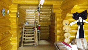 A log cabin interior with a wooden staircase, a small table with a red cloth, and a wall with circular decorations.