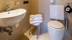 Une salle de bain avec un lavabo blanc, des toilettes et un miroir.