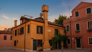 Un bâtiment traditionnel avec un toit en tuiles, une cheminée et une antenne parabolique.