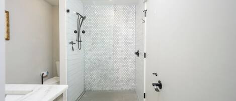 Un baño moderno con ducha, inodoro y lavamanos.