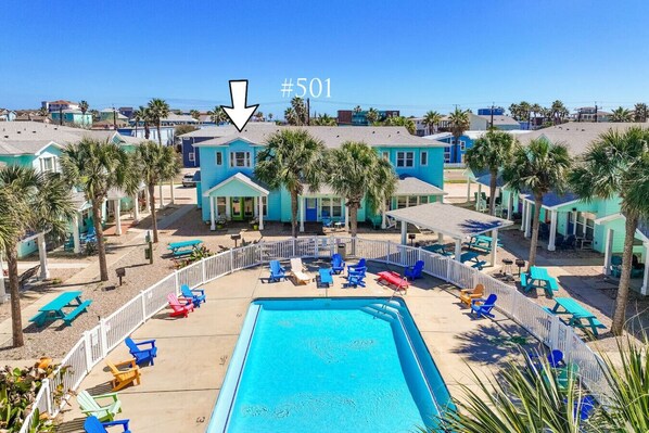 Un resort con piscina rodeada de sillones de playa coloridos y palmeras.