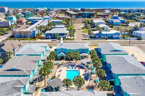 Un resort con piscina central, varias edificaciones y vista al océano.