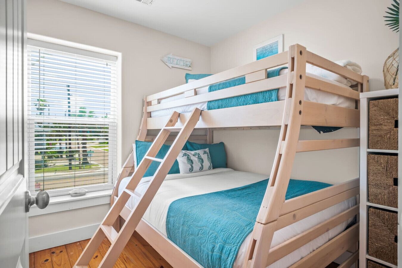 A bunk bed room with a window, a ladder, and storage baskets.
