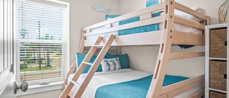 A bunk bed room with a window, a ladder, and storage baskets.