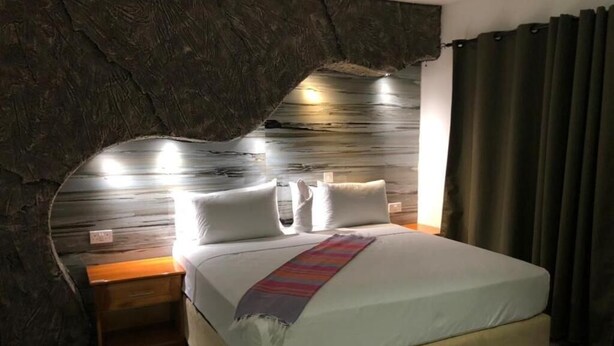A bed with a headboard, bedside tables, and a window with curtains. - Makgadikgadi Riverview Inn (Nata)