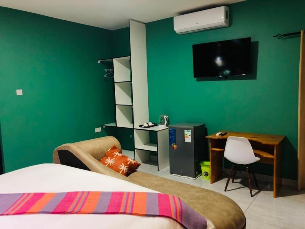 A room with a bed, a desk, a chair, a TV, and a wardrobe.