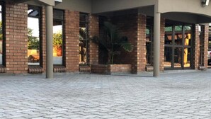 A building entrance with a paved area, brick columns, and a palm tree. - Makgadikgadi Riverview Inn (Nata)