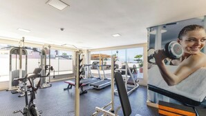 A gym with exercise equipment, large windows, and a view of the outside. - Condominium w/ Pool and Steps fr/ the Beach - Srcs (Ilhéus)