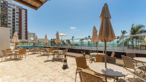 A rooftop terrace with outdoor seating, umbrellas, and a pool view. - Condominium w/ Pool and Steps fr/ the Beach - Srcs (Ilhéus)