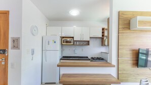 A compact kitchen with white cabinets, a microwave, a gas stove, and a wooden countertop. - Condominium w/ Pool and Steps fr/ the Beach - Srcs (Ilhéus)