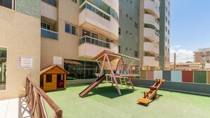 A rooftop playground with a swing set, slide, and small playhouse. - Condominium w/ Pool and Steps fr/ the Beach - Srcs (Ilhéus)