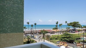 A view of a beach with palm trees, a clear sky, and a building with a tiled facade. - Condominium w/ Pool and Steps fr/ the Beach - Srcs (Ilhéus)