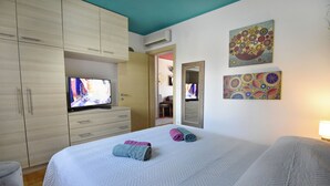 Une chambre d’hôtel équipée d’un lit, d’une télévision, d’une armoire et décorée avec des œuvres d’art.