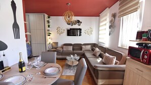Un salon moderne avec un canapé, une table à manger et un téléviseur fixé au mur.