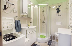 A modern bathroom with a built-in washing machine, a glass-enclosed shower, a toilet, and a sink. - Cozy Flat in Central Umag (Umag)