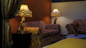 A room with a sofa, two lamps, a vase with flowers, and a bed. - Hostal Cerro Rico (Potosi)