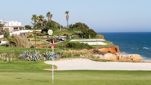 A coastal golf course with a flagstick, sand bunkers, and a clear view of the ocean. - Greice Homes - Villa Carob Tree (Almancil)