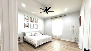 A bedroom with a bed, ceiling fan, and wall-mounted pictures. - Stonewood Cottage  Magnolia/Baylor/Downtown Waco (Waco)