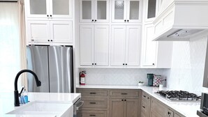 A modern kitchen with white cabinetry, a stainless steel refrigerator, a gas stove, and a built-in oven. - Stonewood Cottage  Magnolia/Baylor/Downtown Waco (Waco)