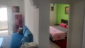 A room with a blue sofa, a bed with a checkered bedspread, and a green wall. - Apartment center agdal (Rabat)
