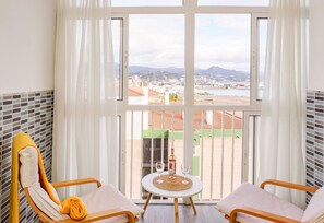 Un balcone con due sedie, un tavolino e una bottiglia di vino.