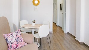 Un comedor con una mesa redonda, sillas blancas y una pequeña planta en maceta.
